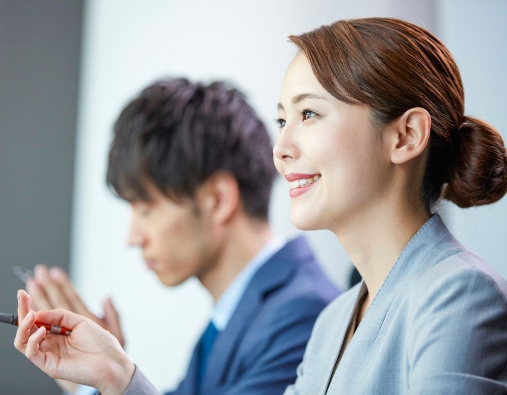 A confident professional in their late 30s smiling during a business meeting.